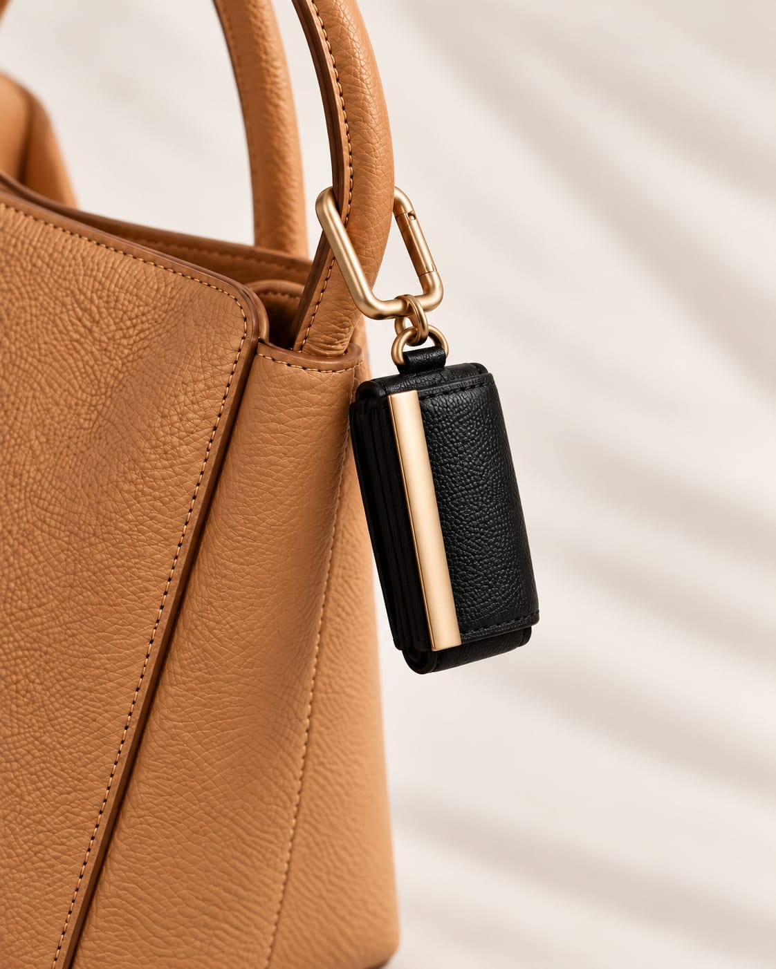Opgerolde zwarte keychain aan een cognac handtas, close-up