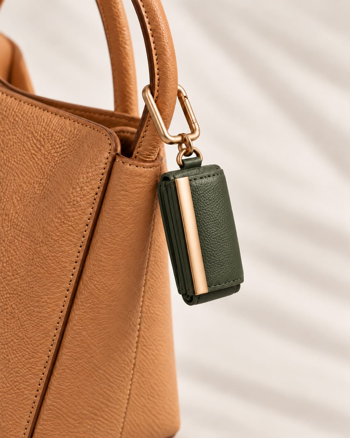 Opgerolde Army Green keychain aan een cognac handtas, close-up