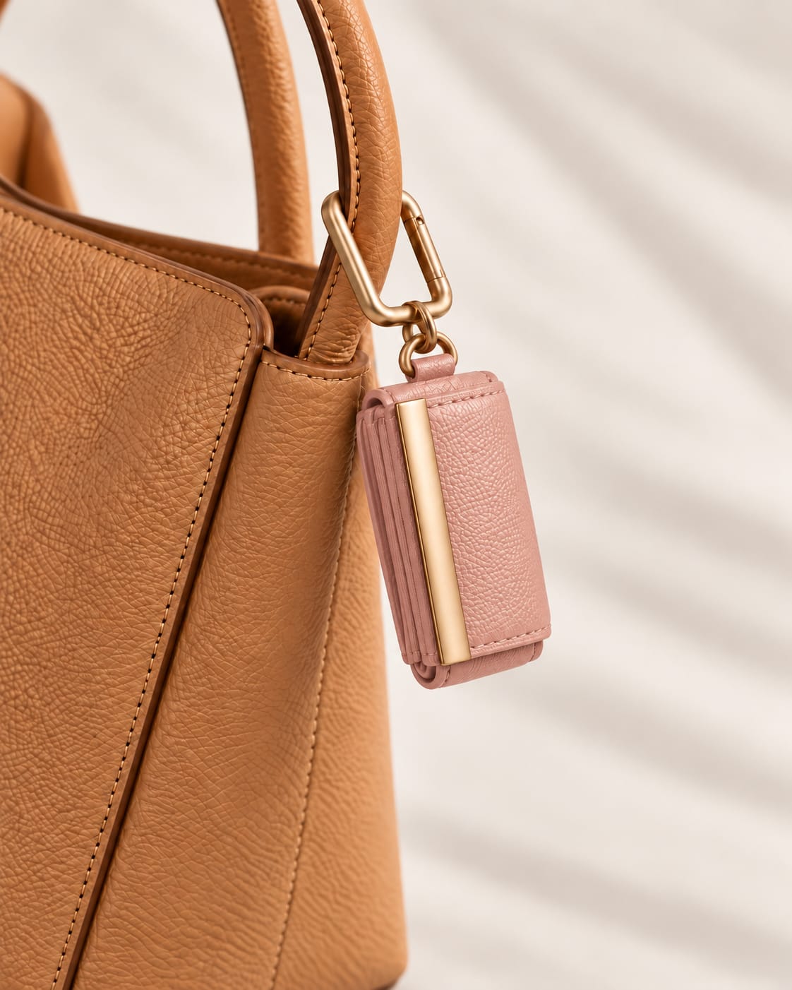 Opgerolde Blush Pink keychain aan een cognac handtas, close-up
