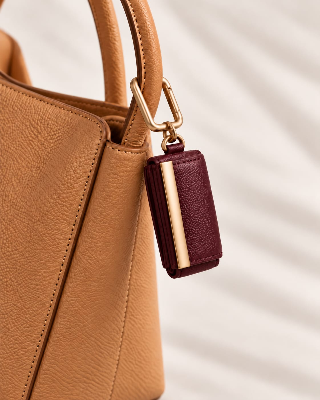 Opgerolde Burgundy keychain aan een cognac handtas, close-up