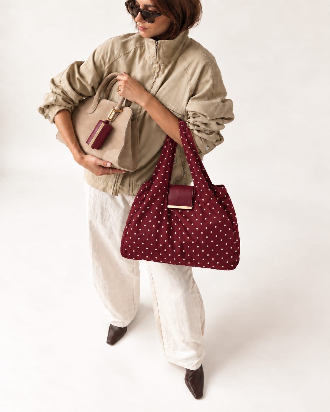Model met de uitgevouwen Burgundy Polka-dot tote en het opgerolde hoesje