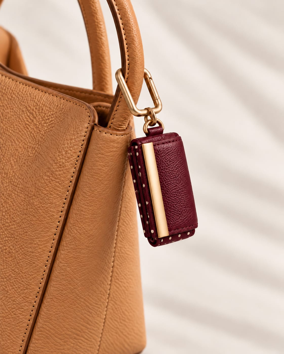 Opgerolde Burgundy Polka-dot keychain aan een cognac handtas, close-up
