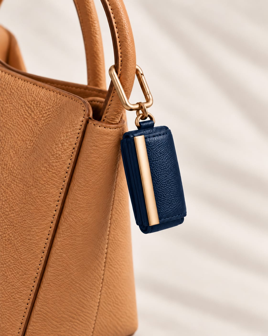 Opgerolde Dark Blue keychain aan een cognac handtas, close-up